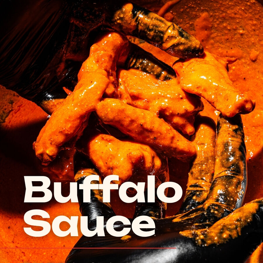 Buffalo sauce wings being tossed by hand